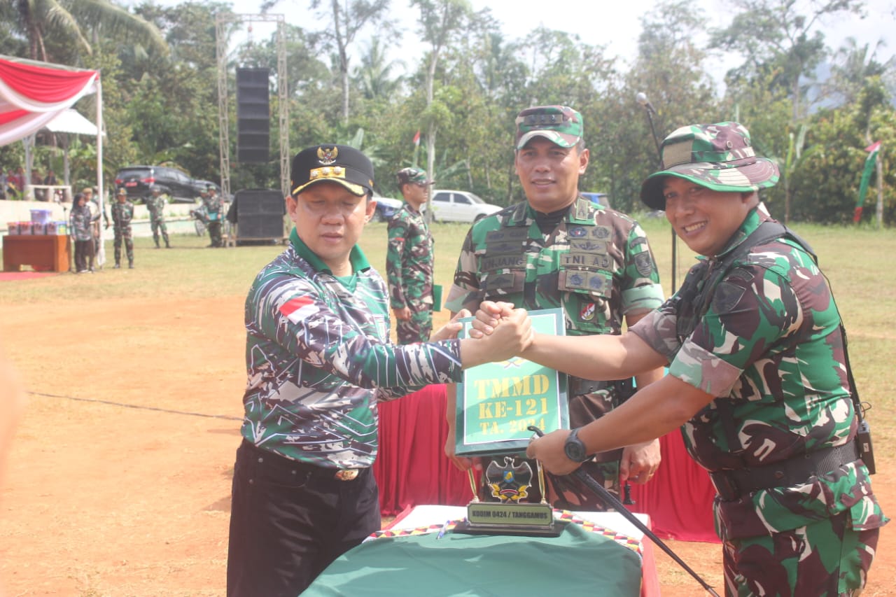 instruksi.co.id,Lampung – Mewakili Komandan Korem 043/Gatam Brigjen TNI Rikas Hidayatullah, S.E., M.M., Kasrem 043/Gatam Kolonel Inf Enjang, S.I.P., M.Han., Kamis (22/08/2024) resmi menutup TNI Manunggal Membangun Desa (TMMD) Ke-121 TA. 2024 Kodim 0424/TGM, adapun tema yang diangkat pada TMMD Ke-121 TA. 2024, yaitu ”Darma Bakti TMMD Mewujudkan Percepatan Pembangunan di Wilayah". Upacara penutupan dilaksanakan di lapangan Pekon Fajar Mulia, Pagelaran Utara Kabupaten Pringsewu dan dihadiri Pj. Bupati Pringsewu Dr. Marindo Kurniawan, S.T., M.M., Ketua DPRD Kabupaten Pringsewu, Kasiren Korem 043/Gatam, Kasipers Kasrem 043/Gatam, Dandim 0424/TGM, Wakapolres Pringsewu, Forkopimda Kabupaten Pringsewu, Para Alim Ulama, Tokoh Masyarakat dan Tokoh Pemuda serta tamu undangan lainnya. Pangdam II/Sriwijaya Mayjen TNI M. Naudi Nurdika, S.I.P., M.Si., M.Tr(Han)., dalam sambutannya, menyampaikan kegiatan TMMD ini dilaksanakan secara serentak di 5 (lima) Kabupaten, yaitu Kabupaten Rejang Lebong wilayah Kodim 0409/RL Korem 041/Gamas, Kabupaten Muaro Jambi wilayah Kodim 0415/Jambi Korem 042/Gapu, Kabupaten Pringsewu wilayah Kodim 0424/TGM Korem 043/Gatam, Kabupaten Banyuasin wilayah Kodim 0430/BA Korem 044/Gapo dan Kabupaten Bangka Tengah wilayah Kodim 0413/Bangka Korem 045/Gaya. “Program TNI Manunggal Membangun Desa Ke-121 TA. 2024 merupakan program yang dilaksanakan lintas sektoral dengan melibatkan pemda, Polri, instansi terkait dan masyarakat setempat, bertujuan membantu pemerintah daerah mempercepat akselerasi pembangunan, terutama membangun infrastruktur, membuka daerah yang terisolir dan tertinggal, guna meningkatkan kesejahteraan masyarakat serta untuk kepentingan pertahanan dan tetap terpeliharanya kemanunggalan TNI-Rakyat.“ “Kita patut berbangga, program TNI Manunggal Membangun Desa di wilayah Sumatera bagian selatan dari tahun ke tahun menunjukkan hasil yang memuaskan, kegiatan TMMD ini dilaksanakan selama satu bulan, mulai tanggal 24 Juli sampai dengan 22 Agustus 2024, hasilnya kian dirasakan manfaatnya oleh masyarakat,“ jelasnya. Selaku pengendali kegiatan operasional TMMD, Pangdam juga mengucapkan terima kasih dan apresiasi yang setinggi-tingginya kepada para Gubernur serta Forkopimda Provinsi, Kapolda beserta jajarannya, Bupati beserta Forkopimda Kabupaten, instansi kementerian terkait dan khususnya kepada seluruh masyarakat, yang telah bahu-membahu bersama prajurit TNI, mewujudkan pembangunan daerah yang menjadi sasaran pelaksanaan TMMD Ke-121 TA. 2024. “Pada setiap kegiatan TMMD, kita dapat menyaksikan semangat kebersamaan serta gotong-royong yang terpancar di setiap wajah dan cucuran keringat masyarakat dan aparat yang bersama-sama bekerja di lapangan, hal ini menjadi refleksi kekuatan yang sangat besar dari segenap komponen bangsa, yang memiliki visi, misi dan tujuan bersama guna mengatasi berbagai persoalan kesejahteraan masyarakat.“ “Dengan telah berakhirnya TMMD Ke-121 ini, saya berpesan kepada kita semua, khususnya kepada anggota satgas TMMD dan segenap masyarakat, agar terus memelihara semangat kebersamaan dan kemanunggalan TNI-Rakyat, tingkatkan semangat untuk bekerja dan membangun bersama, sebagai realisasi semangat gotong royong, dan pelihara hasil-hasil program TMMD Ke-121 ini dengan sebaik-baiknya, selanjutnya, mewakili seluruh prajurit dan satgas TMMD Ke-121 saya memohon maaf, apabila selama pelaksanaan TMMD ada tingkah laku dan tindakan yang kurang berkenan di hati masyarakat,“ pungkasnya. Usai dilaksanakan upacara penutupan, Kasrem 043/Gatam Kolonel Inf Enjang, S.I.P., M.Han., Pj. Bupati Pringsewu Dr. Marindo Kurniawan, S.T., M.M., Ketua DPRD beserta Forkopimda Kabupaten Pringsewu, menyerahkan bingkisan kepada masyarakat Pekon Fajar Mulia, dilanjutkan meninjau lokasi TMMD, meninjau posko kesehatan dan UMKM.(Suhartono/rls)