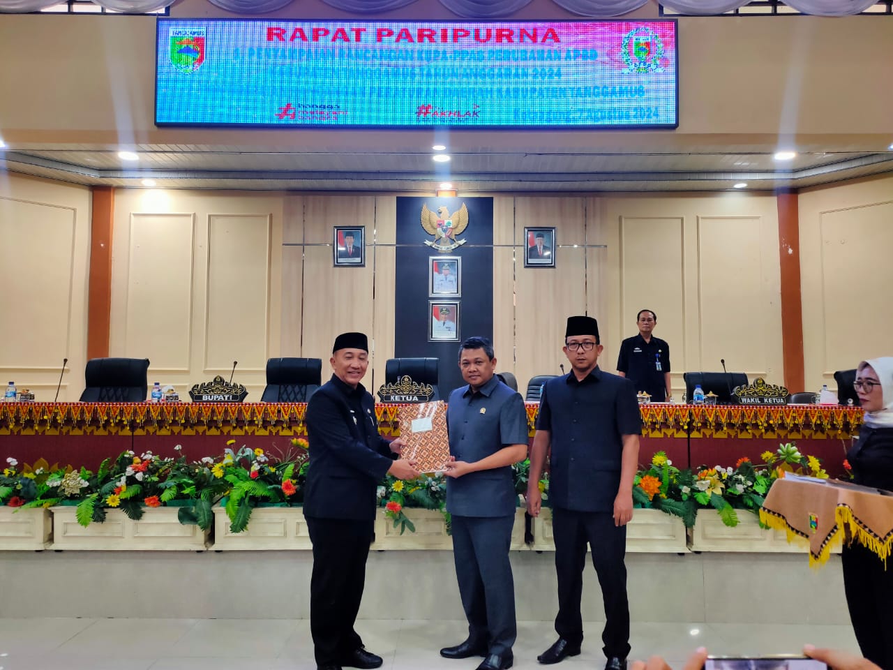 instruksi.co.id, Tanggamus - Dewan Perwakilan Rakyat Daerah (DPRD) Kabupaten Tanggamus, menggelar Rapat Paripurna Penyampaian Rancangan Kebijakan Umum Perubahan Anggaran (KUPA) serta Rancangan Prioritas dan Plafon Anggaran Sementara Perubahan (PPAS-P) Kabupaten Tanggamus Tahun Anggaran 2024, sekaligus juga dirangkaikan dengan Penyampaian Rancangan Peraturan Daerah Tentang Pengelolaan Air Limbah Domestik. Bertempat di Ruang Sidang DPRD Tanggamus. Rabu (7/8/2024) Rapat paripurna yang berlangsung di Ruang Sidang DPRD Tanggamus itu dipimpin Ketua DPRD Tanggamus Heri Agus Setiawan, S.Sos., didampingi Wakil Ketua I DPRD Tanggamus Irwandi Suralaga, S.Ag itu dihadiri 27 Anggota DPRD Tanggamus serta dihadiri Pj Bupati Tanggamus Dr.Ir. Mulyadi Irsan, MT. Turut hadir anggota Forkopimda, Pj Sekretaris Daerah, Para Asisten, Staf Ahli, Pimpinan Instansi Vertikal, Kepala Perangkat Daerah, Camat, Apdesi, Tokoh Masyarakat, Insan Pers dan unsur Ormas. Pj Bupati Tanggamus Dr.Ir. Mulyadi Irsan, MT., menjelaskan terkait Rancangan KUPA dan PPAS-P Tahun Anggaran 2024, dalam Undang-Undang Nomor 23 Tahun 2014 tentang Pemerintahan Daerah, fungsi Pemerintah Daerah dan DPRD dalam pembangunan adalah meningkatkan kesejahteraan masyarakat, yang dimuat dalam dokumen kebijakan pembangunan sebagai hasil dari kristalisasi aspirasi masyarakat. Hal tersebut juga sejalan dengan esensi pembangunan yang merupakan aktivitas yang berjalan secara simultan, meliputi perencanaan, pelaksanaan, dan evaluasi. Penyusunan Rancangan KUPA serta Rancangan PPAS-P Kabupaten Tanggamus Tahun Anggaran 2024 ini dilaksanakan berdasarkan Peraturan Pemerintah Nomor 12 Tahun 2019 Tentang Pengelolaan Keuangan Daerah serta Peraturan Menteri Dalam Negeri Nomor 77 Tahun 2020 tentang Pedoman Teknis Pengelolaan Keuangan Daerah. Dalam Peraturan Menteri tersebut mengatur bahwa pemerintah daerah bersama dengan DPRD dapat melakukan perubahan APBD apabila terjadi hal-hal sebagai berikut: Pertama, perkembangan yang tidak sesuai dengan asumsi kebijakan umum anggaran yang telah ditetapkan pada tahun sebelumnya. Kedua, keadaan yang menyebabkan harus dilakukan pergeseran anggaran antar unit organisasi, antar kegiatan dan antar jenis belanja. Ketiga, Saldo Anggaran Lebih Tahun Sebelumnya yang harus digunakan untuk tahun berjalan. Sejalan dengan tema dan prioritas pembangunan Tahun 2024, maka Pemerintah Daerah Kabupaten Tanggamus telah menyusun Rancangan KUPA dan PPAS-P Tahun Anggaran 2024 dengan ringkasan sebagai berikut: Pertama, Pendapatan Daerah Kabupaten Tanggamus Tahun Anggaran 2024 diproyeksikan mengalami perubahan dari semula Rp.1.802.316.876.174 menjadi Rp.1.802.166.673.574 atau berkurang sebesar Rp.150.202.600. Kemudian, Belanja Daerah Kabupaten Tanggamus Tahun Anggaran 2024 diproyeksikan mengalami perubahan dari Rp.1.783.402.490.691 menjadi Rp.1.804.199.625.181 atau bertambah sebesar Rp.20.797.134.490. Selanjutnya, Pembiayaan Daerah Kabupaten Tanggamus Tahun Anggaran 2024 terdiri dari: Penerimaan Pembiayaan, diproyeksikan meningkat dari Rp.4.121.493.000 menjadi Rp.25.068.830.090 yang merupakan sisa lebih perhitungan anggaran tahun sebelumnya, berdasarkan hasil audit BPK. Pengeluaran Pembiayaan, diproyeksikan tetap sebesar Rp.23.035.878.483, dipergunakan untuk pembayaran cicilan pokok hutang PEN. Pembiayaan total, diproyeksikan Surplus Rp.2.032.951.607, dimana pembiayaan total ini untuk menutup defisit anggaran yang terjadi. "Dengan kondisi tersebut, maka Rancangan KUPA dan PPAS-P Kabupaten Tanggamus Tahun Anggaran 2024 diproyeksikan tetap dalam kondisi anggaran berimbang antara Pendapatan, Belanja dan Pembiayaan Daerah," kata Pj Bupati Tanggamus. Selanjutnya terkait Ranperda Tentang Pengelolaan Air Limbah Domestik, perlu kita buatkan Perda, karena Undang-Undang Dasar Negara Republik Indonesia Tahun 1945 meng-amanat-kan bahwa setiap warga negara berhak untuk hidup sejahtera lahir dan batin, bertempat tinggal, dan mendapatkan lingkungan hidup yang baik dan sehat. Oleh karena itu, pemerintah terutama pemerintah daerah memberikan upaya dalam mendukung kesejahteraan tersebut dengan skema-skema kebijakan publik yang mendukung lingkungan hidup. Salah satu upaya tersebut adalah dengan adanya Pengelolaan Air Limbah Domestik di wilayah Kabupaten Tanggamus. Kewenangan Pemerintah Daerah dalam menetapkan Pengelolaan Air Limbah Domestik ini diatur oleh Undang-Undang Nomor 23 Tahun 2014 tentang Pemerintahan Daerah, yang menyebutkan bahwa Pembagian Urusan Pemerintahan Konkuren menempatkan Kewenangan Pengelolaan dan Pengembangan Sistem Air Limbah Domestik diatur oleh Pemerintah Daerah Kabupaten/Kota. Air limbah domestik adalah air limbah yang berasal dari usaha dan/atau kegiatan pemukiman, rumah makan, perkantoran, perniagaan, apartemen, dan asrama. Saat ini, air limbah domestik yang dibuang ke media lingkungan hidup semakin meningkat dan berpotensi menimbulkan kerusakan dan pencemaran lingkungan. Untuk mengatasi hal ini diperlukan sebuah sistem air limbah skala permukiman, yakni sebuah sistem pelayanan sanitasi yang melayani sekelompok rumah tangga, memiliki jaringan pipa, dan unit pengolahan air limbah. Walaupun penyusunan Ranperda ini telah mempertimbangkan berbagai aspek, namun demi kesempurnaan produk hukum yang akan kita berlakukan, maka Ranperda Tentang Pengelolaan Air Limbah Domestik diperlukan masukan dan saran dari Dewan Yang Terhormat, sehingga pada saatnya nanti dapat disetujui dan ditetapkan menjadi Peraturan Daerah Kabupaten Tanggamus, yang Insha Allah akan memberikan manfaat bagi pembangunan daerah di Kabupaten Tanggamus, Tutup Pj Bupati". (Teddi)