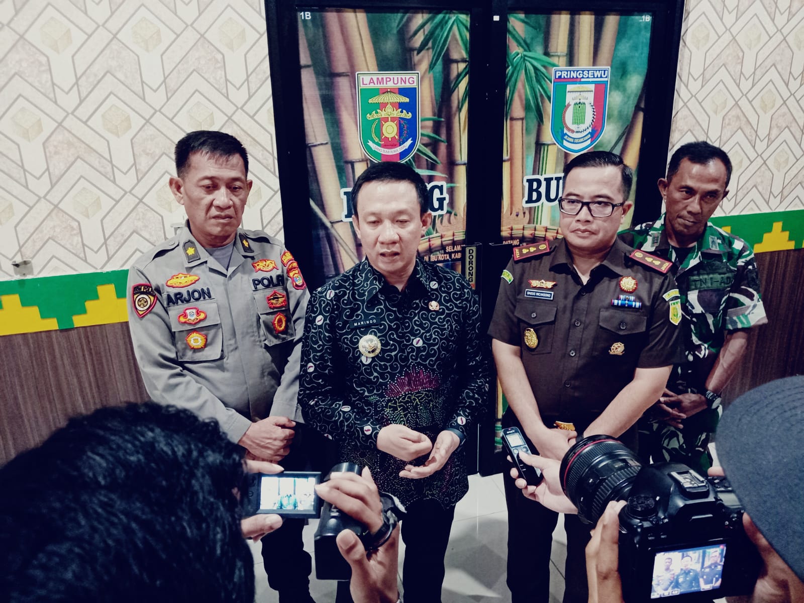 instruksi.co.id, Pringsewu – Pemerintah Kabupaten (Pemkab) Pringsewu bersama Kejaksaan Negeri (Kejari) Pringsewu melaunching Program Jaksa Garda Desa (Jaga Desa). Acara launching sekaligus penandatanganan kerjasama kedua institusi oleh Pj.Bupati Pringsewu Marindo Kurniawan dan Kajari Pringsewu Raden Wisnu Bagus Wicaksono dalam rangka Optimalisasi Dalam Membangun Kesadaran Hukum Penyelenggara Pemerintahan Desa dan Masyarakat dilaksanakan di Aula Utama Pemkab Pringsewu, Kamis (22/8/2024). Pj.Bupati Pringsewu Marindo Kurniawan mengatakan digulirkannya Program Jaksa Garda Desa yang merupakan bentuk optimalisasi dan meningkatkan kesadaran hukum para penyelenggara pemerintahan pekon dan masyarakat, dapat mencegah terjadinya penyimpangan dalam pengelolaan keuangan pekon. “Yakni melalui optimalisasi pengawalan, asistensi, bimbingan, penyuluhan hukum dan penerangan hukum pada penyelenggara pemerintahan pekon dan masyarakat dalam pengelolaan keuangan pekon, pelayanan dan pendampingan hukum, dengan melibatkan Kejari Pringsewu,” katanya. Untuk itu, ia berharap semua dapat mendukung program tersebut, sehingga kedepan proses penegakan hukum terhadap dugaan penyimpangan pengelolaan keuangan pekon dan berbagai potensi permasalahan hukum yang mungkin terjadi dalam lingkup pekon dapat lebih tertangani dengan efektif dan efisien. “Tentunya dengan mengoptimalkan fungsi Rumah Restorative Justice di setiap pekon sebagai tempat berkumpulnya masyarakat pekon untuk menyerap aspirasi secara langsung dari tokoh agama, tokoh adat dan tokoh masyarakat bagi menyelaraskan nilai-nilai kearifan lokal yang dapat digunakan untuk mengambil keputusan dalam proses hukum yang bersifat Keadilan Restoratif,” ujarnya. Melalui kesepakatan bersama tersebut, para penyelenggara pemerintahan pekon dan masyarakat diharapkan dapat lebih memahami aturan-aturan yang berlaku sehingga dalam menjalankan tugas dan kewenangannya dapat berjalan sesuai aturan yang berlaku guna meningkatkan pelayanan kepada masyarakat dalam mewujudkan Wilayah Bebas Korupsi (WBK) dan Wilayah Birokrasi Bersih Melayani (WBBM). “Semoga kerjasama ini dapat berjalan dengan baik dan berkelanjutan, sehingga mendatangkan manfaat seluas-luasnya bagi pembangunan di Kabupaten Pringsewu dimasa yang akan datang,” ucapnya. Sementara itu, Kajari Pringsewu Raden Wisnu Bagus Wicaksono kepada pers selepas acara penandatanganan perjanjian kerjasama tersebut mengatakan Jaksa Garda Desa merupakan instruksi Jaksa Agung RI No.5 Tahun 2023 tentang Optimalisasi Peran Kejaksaan RI dalam Membangun Kesadaran Hukum Masyarakat Desa, sebagai upaya secara preventif kepada para kepala desa dalam pengelolaan Dana Desa. “Fokus utama kita adalah bagaimana mengawal keuangan yang bersumber dari negara melalui Dana Desa maupun Alokasi Dana Desa. Kami selalu senantiasa bersinergi dalam hal ini Inspektorat terkait bagaimana pengelolaan yang ada di Kabupaten Pringsewu. Kalau dalam evaluasi itu bagus ya kita kawal, dan kalaupun ada yang menyimpang nanti kita luruskan,” ujarnya. Turut hadir pada kesempatan tersebut, Ketua DPRD Pringsewu diwakili Wakil Ketua Komisi I Anton Subagyo, Kapolres Pringsewu diwakili Kabag SDM Kompol Arjon Syafri, Dandim 0424/TGM diwakili Danramil 424-06 Pringsewu Kapten Inf.Rahmad, beserta jajaran Pemerintah Daerah, Camat serta Kepala Pekon dan Lurah se-Kabupaten Pringsewu. (Hikmah/Ant)